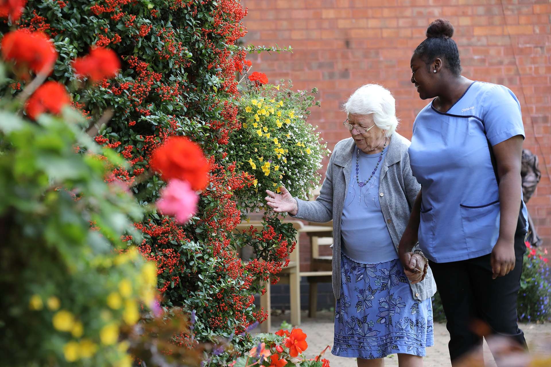 CCH Kingsleigh Gallery Image displaying a resident talking about the flowers in the garden to a carer