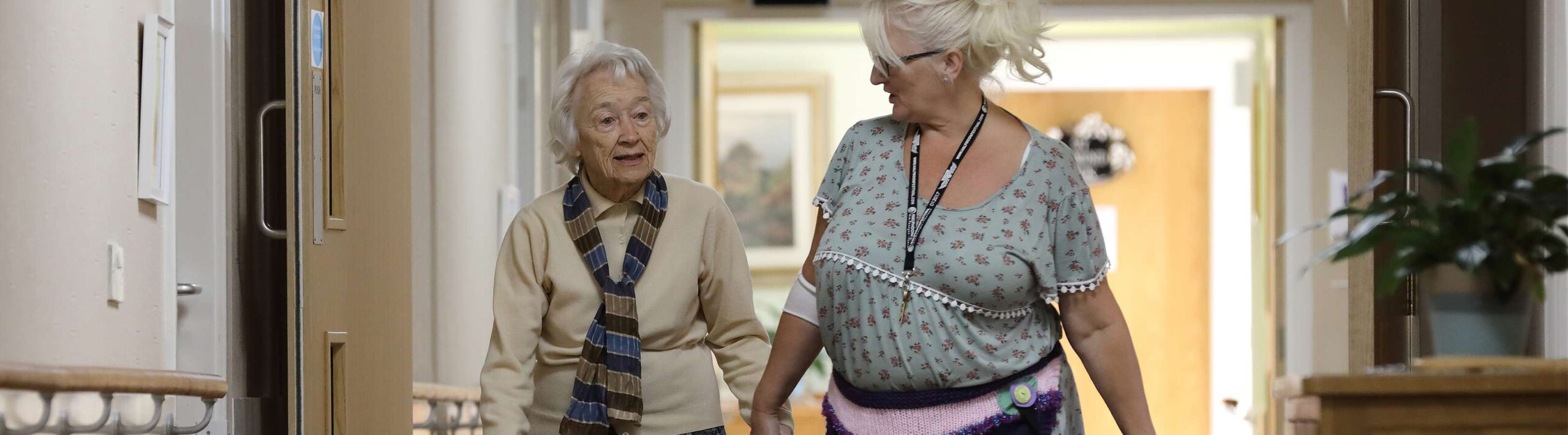 CCH Olivet Banner image showing a carer holding a residents hand whilst walking and talking